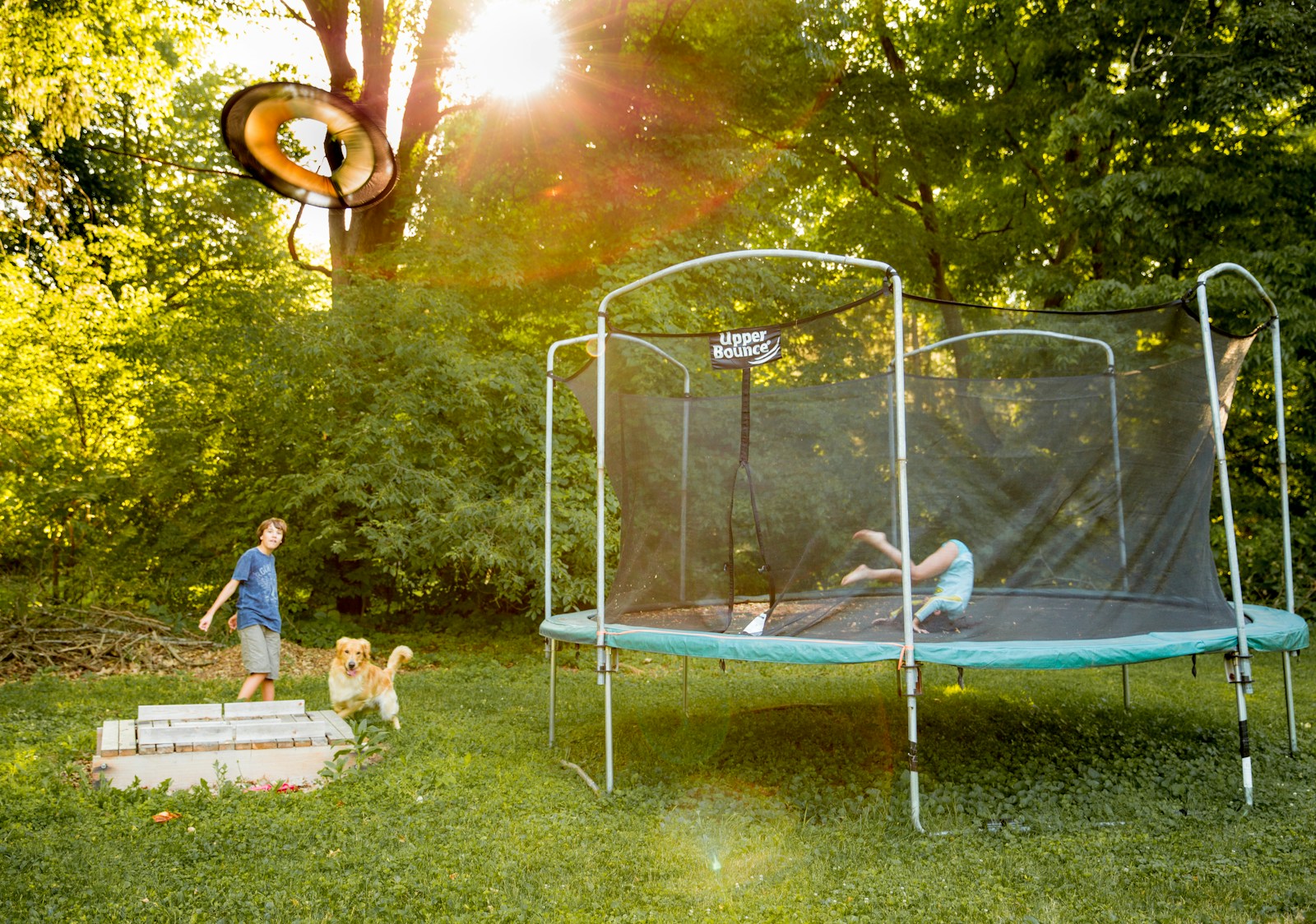 two children playing on a trampoline in a yard