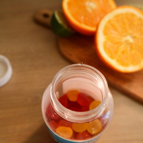 a jar filled with gummy bears next to sliced oranges